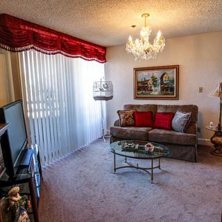 A cozy living room with classic decor featuring a chandelier, sofa, and coffee table.