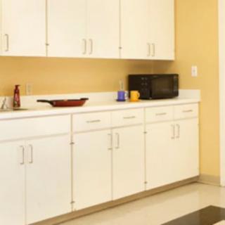 A kitchen with white cabinets and a countertop featuring a microwave.