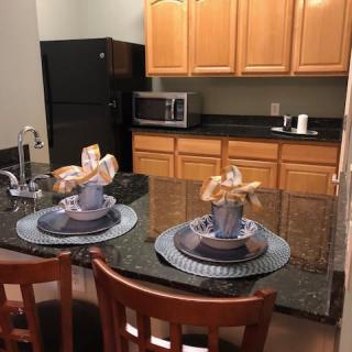 A cozy kitchen setup with a granite countertop, complete with decorative table settings and wooden cabinetry.