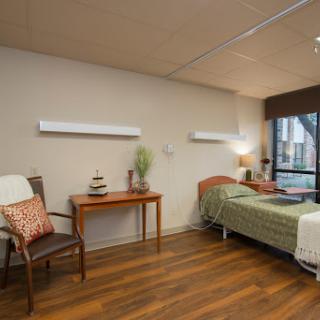 A well-lit hospital room featuring a bed, a chair, and decorative elements.
