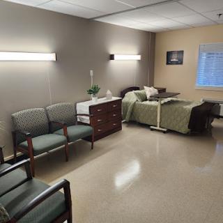 A well-organized hospital room featuring a patient bed, seating area, and essential furnishings.