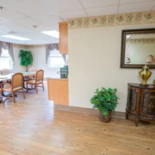 A cozy and well-decorated interior space featuring a dining area with wooden furniture, decorative plants, and a wall mirror.