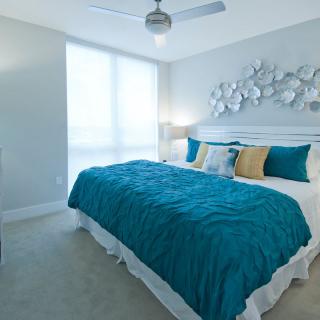 A modern bedroom with teal and white decor featuring a comfortable bed.