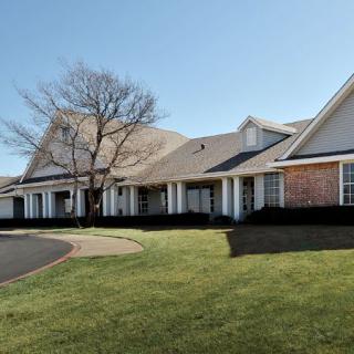 A suburban residential building with a well-maintained lawn and driveway on a clear day.