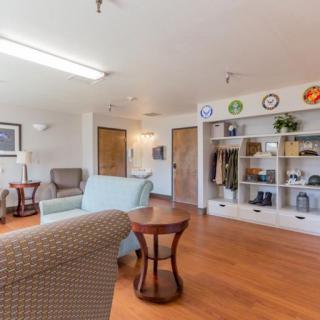 A cozy living room featuring comfortable seating, wooden floors, and a shelf with decorative items.