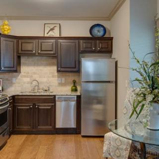 A modern kitchen featuring dark wooden cabinets and stainless steel appliances, complemented by a cozy dining area.