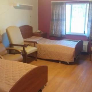 A cozy bedroom with twin beds and chairs, featuring a large window with curtains.