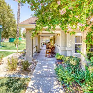 A cozy porch with rocking chairs surrounded by lush greenery and a well-maintained garden path.