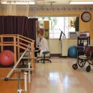 A rehabilitation room equipped with parallel bars, exercise balls, and a walker.