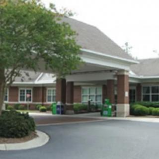 A view of a building entrance with surrounding trees and a paved driveway.
