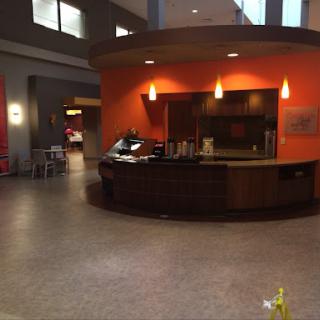 A modern reception area featuring a circular front desk and vibrant orange walls.