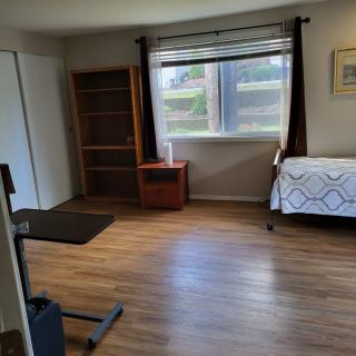 Spacious bedroom with wooden flooring, a bed, and large window.