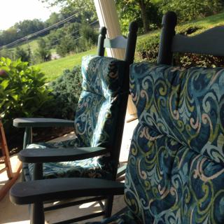 Rocking chairs with patterned cushions on a sunny porch.