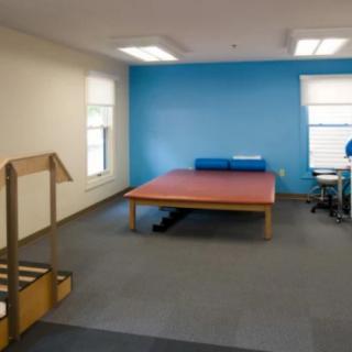 A physical therapy room featuring exercise equipment and a large padded table.