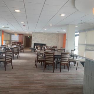 A spacious and modern dining area with several tables and chairs, featuring laminate flooring and ceiling lights.