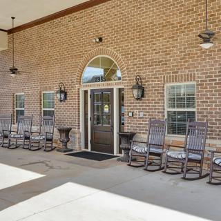 Entrance to a building with a brick facade and outdoor rocking chairs.