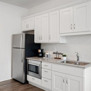 A modern kitchen with white cabinets and stainless steel appliances.