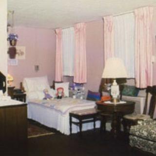 A cozy vintage living room with pink curtains and classic furniture.