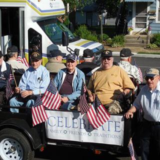 A group of veterans riding in a parade float adorned with American flags, celebrating their service.