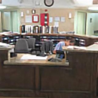 A receptionist working at a large circular desk in an office setting.