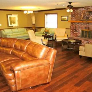 A cozy living room featuring a leather sofa, brick fireplace, and hardwood flooring.