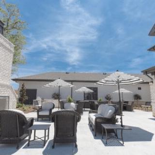 A modern outdoor patio area with comfortable seating and umbrellas on a sunny day.