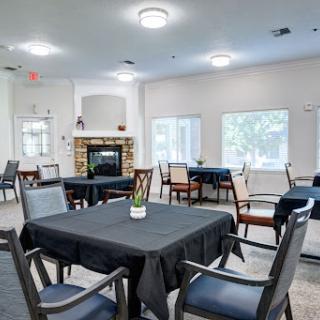 A spacious and bright dining room featuring black tablecloths, elegant furniture, and a cozy fireplace.