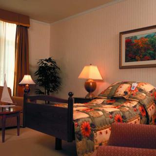 A cozy bedroom with a floral bedspread, illuminated by warm lighting from table lamps.