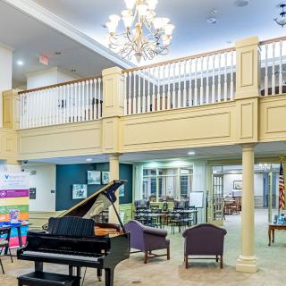 A spacious lobby featuring a grand piano, elegant chandelier, and comfortable seating area.