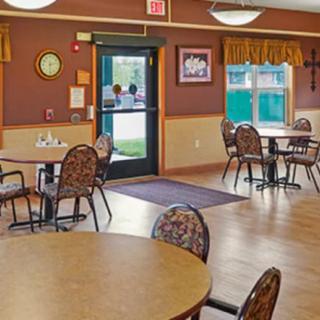 An empty dining room with tables and chairs arranged on a wooden floor.