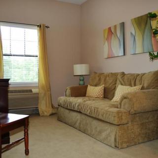 A cozy living room with a beige sofa, colorful artwork, and yellow curtains.
