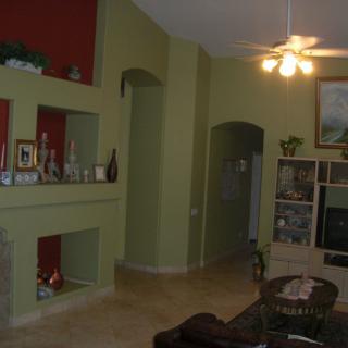 A cozy living room with a unique shelving design and ceiling fan.