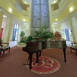 An elegant lobby featuring a grand piano surrounded by plants and sophisticated decor.