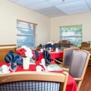 A dining room with elegantly set tables, featuring red tablecloths and folded napkins.