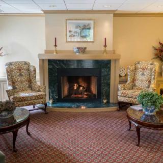 A cozy living room featuring a fireplace with armchairs and a coffee table.