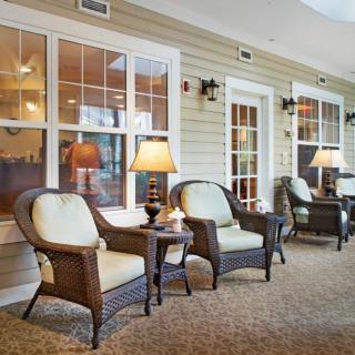 A cozy indoor lounge area with wicker chairs, side tables, and warm lighting.