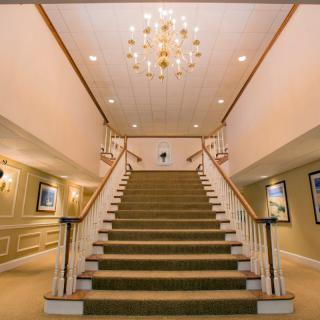 A grand staircase with a chandelier in an elegant interior setting.