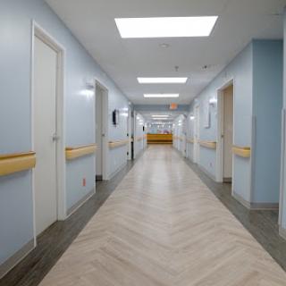 A modern and clean hallway in a hospital, featuring blue walls and ample lighting.