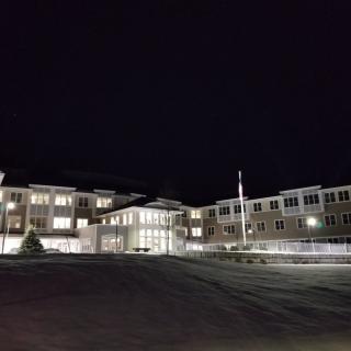 A well-lit building at night with visible entrance and windows.