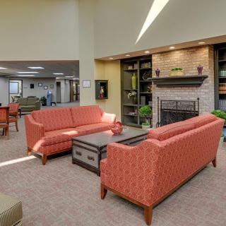 A cozy living room with red couches, a central coffee table, and a brick fireplace surrounded by shelves.