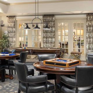 A luxurious room with leather chairs and gaming tables, adorned with elegant lighting and decorative curtains.