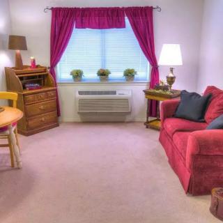 A cozy living room with a red sofa, wooden desk, and vibrant curtains.