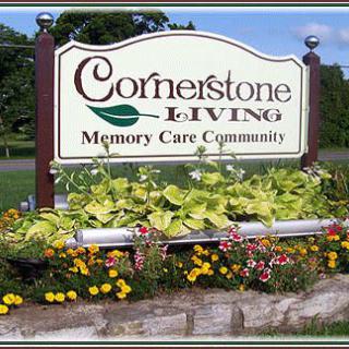 Sign for Cornerstone Living Memory Care Community surrounded by flowers.