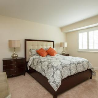 A cozy and elegantly designed bedroom featuring a comfortable bed with decorative pillows, stylish lamps on either side, and ample natural light.