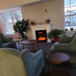 A cozy living room with a fireplace, comfortable seating, and indoor plants.