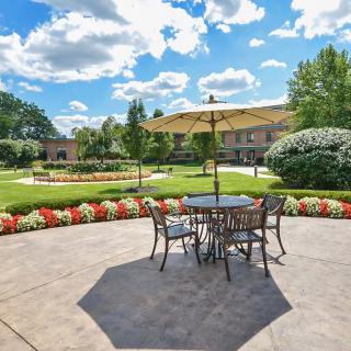 A beautiful patio setting with a table and umbrella overlooking a landscaped garden on a sunny day.
