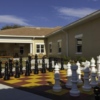 A large outdoor chess set in a sunny courtyard.