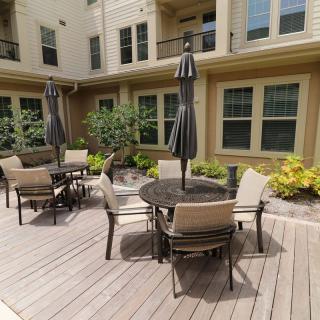 Outdoor patio area with tables and chairs surrounded by apartment building.