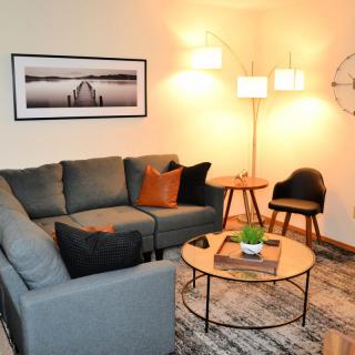 A modern living room with a cozy gray sofa, stylish lamps, and a round coffee table.