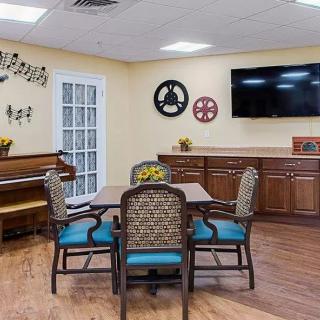 A cozy dining room with a piano, television, and decorative elements.